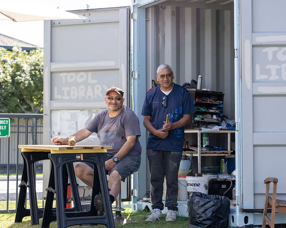 Two smiling men outside the St Mary's Glenn Innes tool library shed