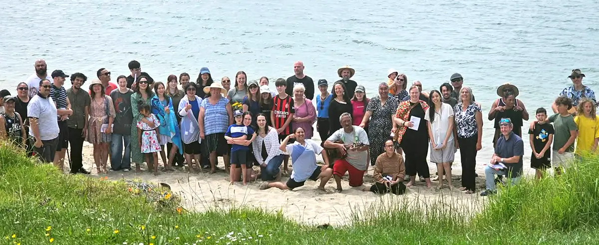 Group of church members posing in a group, with the beach in the background